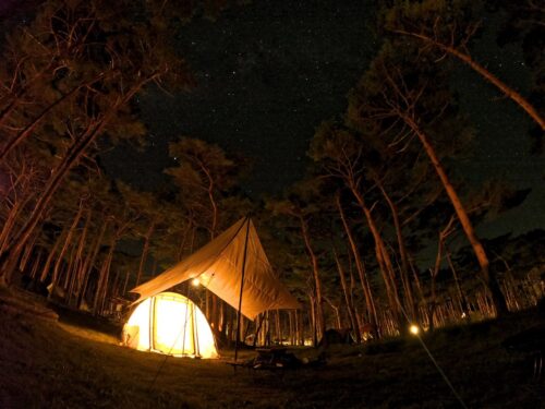 夜にランタンの灯りに照らされたテントとタープ