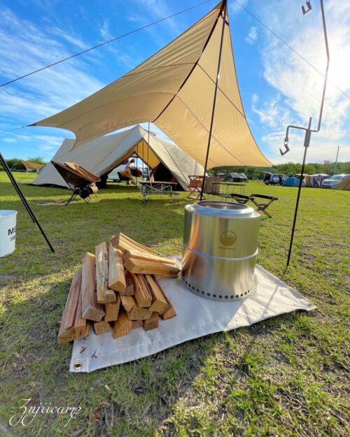 テントとタープを背景にフレイムストーブマックスと薪が置いてある