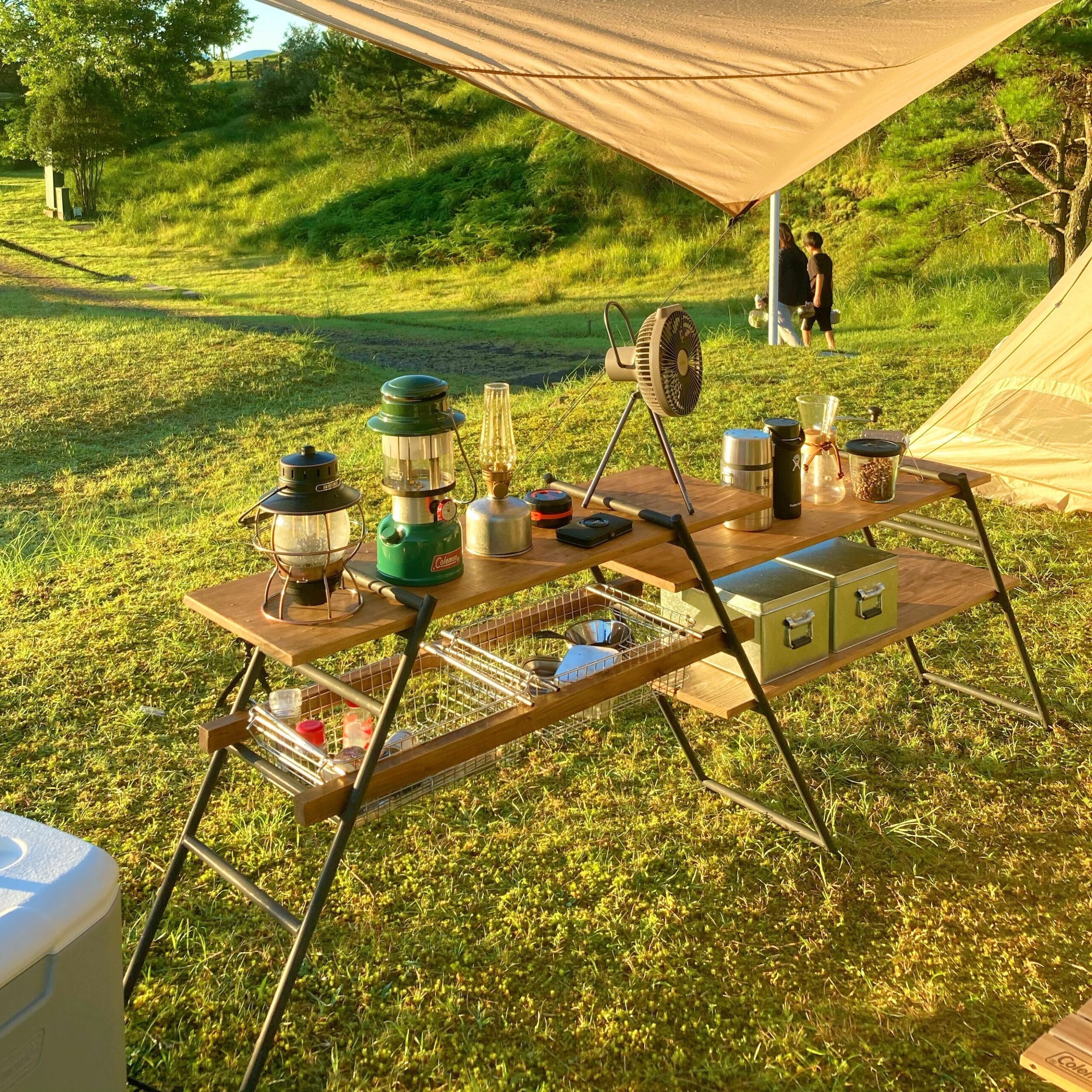 朝露に濡れたタープの下にキャンプ道具を並べているDODテキーラキッチンレッグ