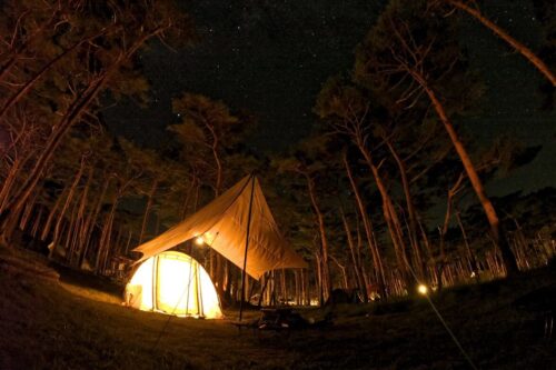 夜にランタンの灯りに照らされたテントとタープ