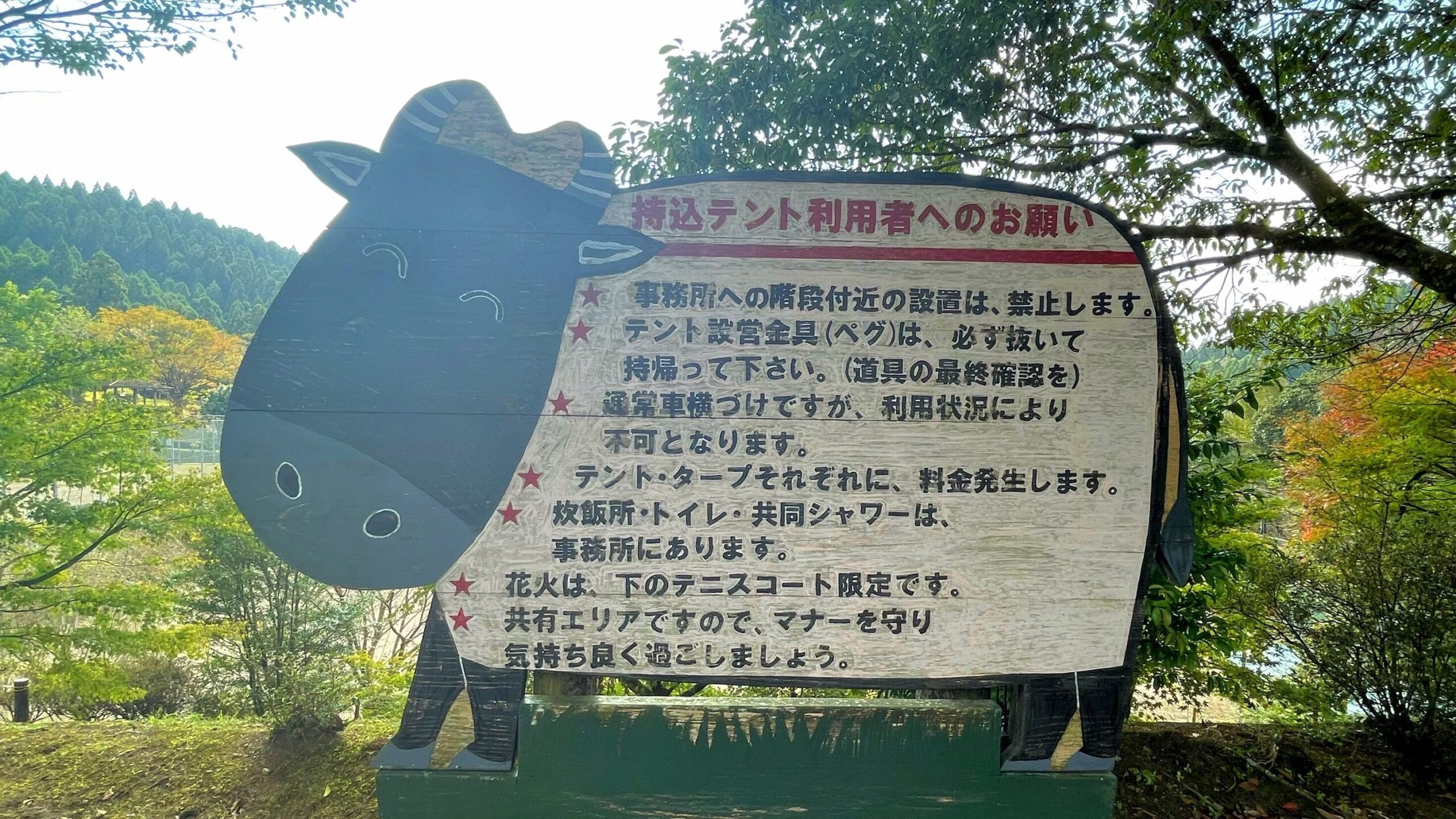 花房峡憩いの森キャンプ場オートキャンプ場多目的広場に立てられている牛の絵の持込テント利用者へのお願いが書かれている看板