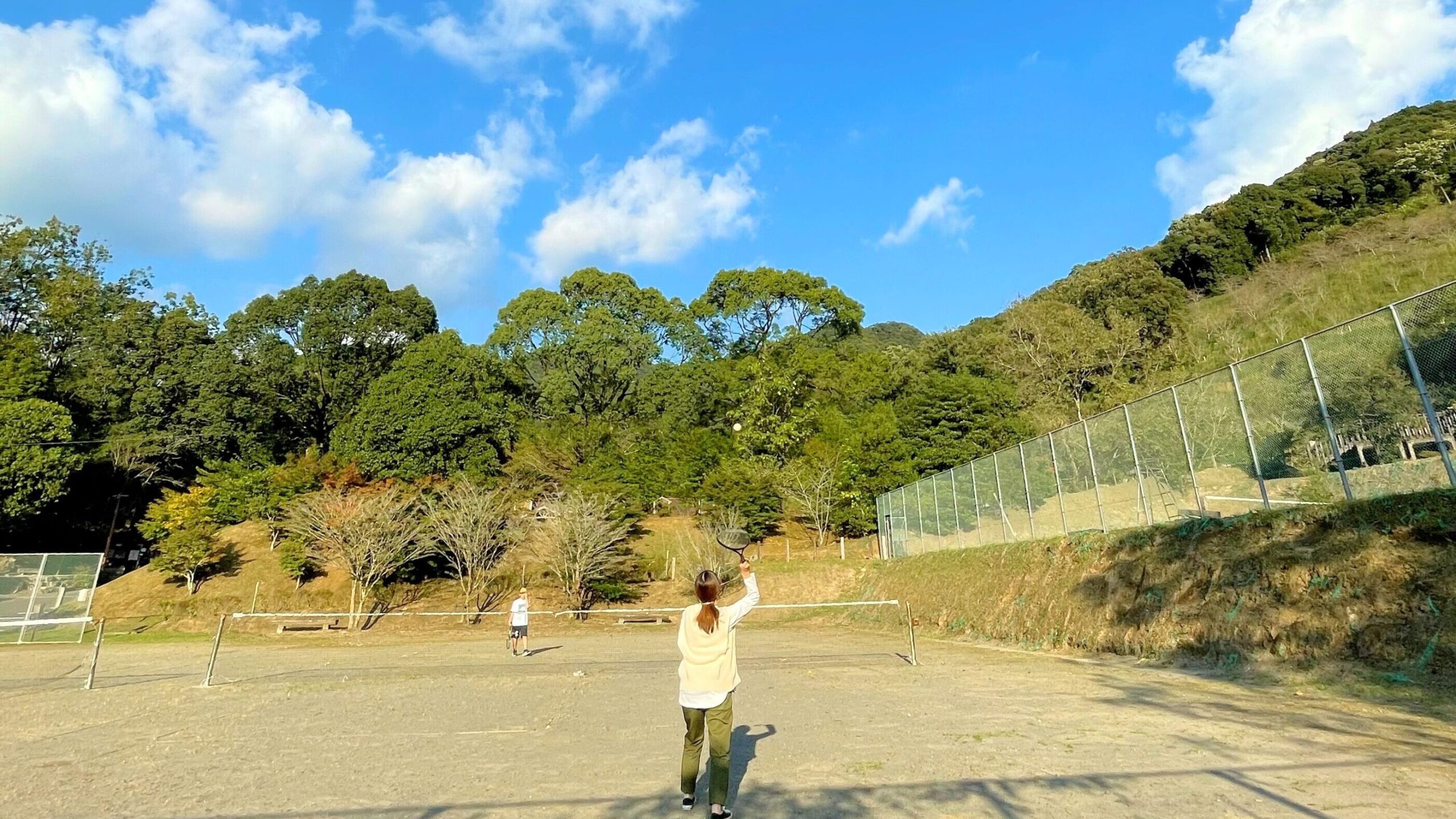 花房峡憩いの森キャンプ場にあるテニスコートでテニスをしている親子
